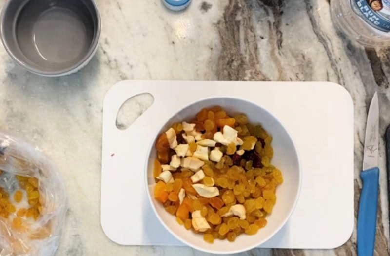 A cutting board filled with dried fruit for making Panettone muffins.