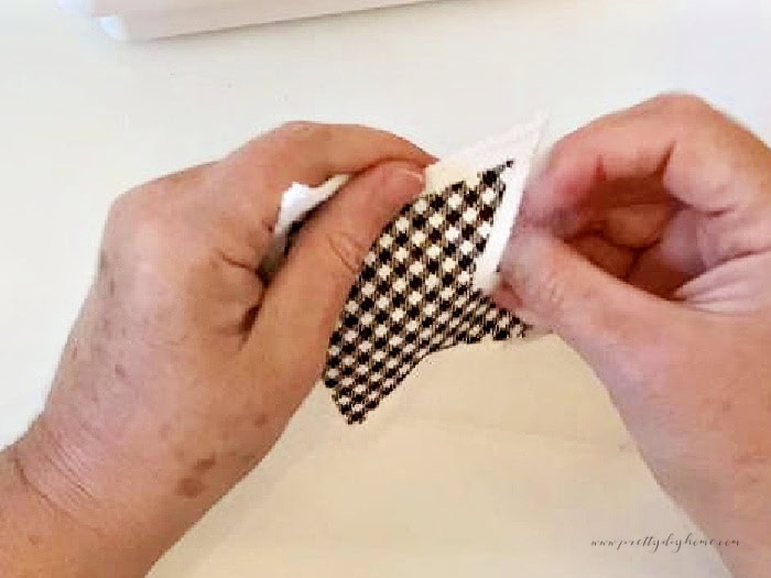 Adding stuffing to the inside of a fabric star.  You can see where the star was left unstitched, and its now being used to stuff with a small piece of polyfil stuffing.