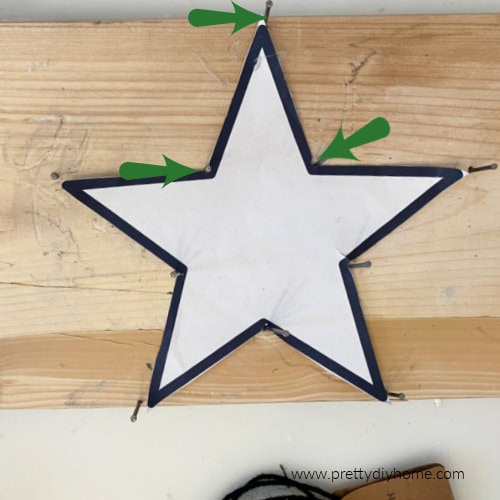 A home made form to fold wire on.  The form is made up of a piece of wood, a star pattern, and nails hammered in at all the points of the star.