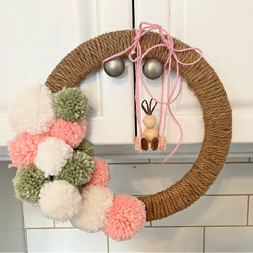 A Easter wreath suspended from kitchen knobs for adjusting the hanging swing to sit properly.