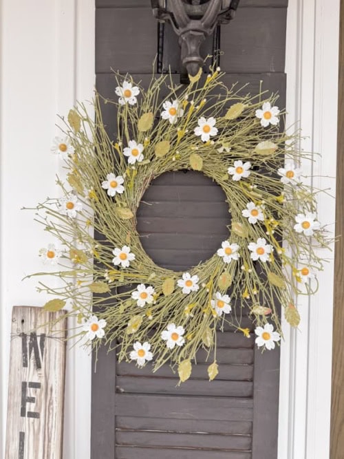 A large Spring wreath with soft green wreath form, bright geeen leaves and diy white diasy flowers with white blossoms and pretty yellow centers.