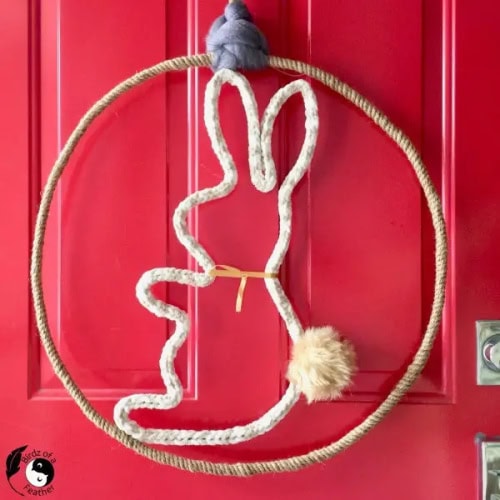 A DIY Spring wreath for the front door. with a hand made bunny silhouette in cream wool and a fluffy bunny tale.