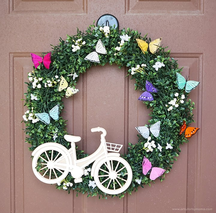 A green wreath for Spring decorated with a large white bicycle, and lots of small flowers and beautiful miniature butterflies. A perfect Spring wreath for the front door.