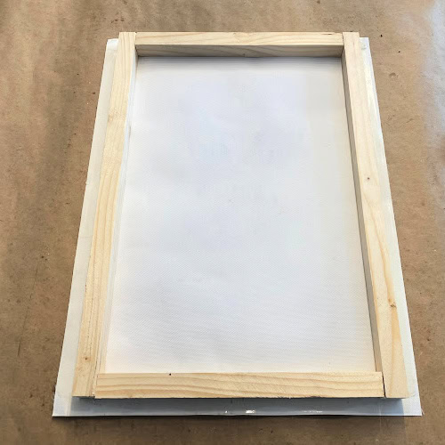 A wooden back center on top of a art canvas for  framing.