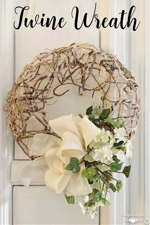 A DIY wreath made with a thick handmade twine frame. The elaborate twine frame is then decorated with a large white flower and cream colored bow. A beautiful neutral Spring wreath for the front door.