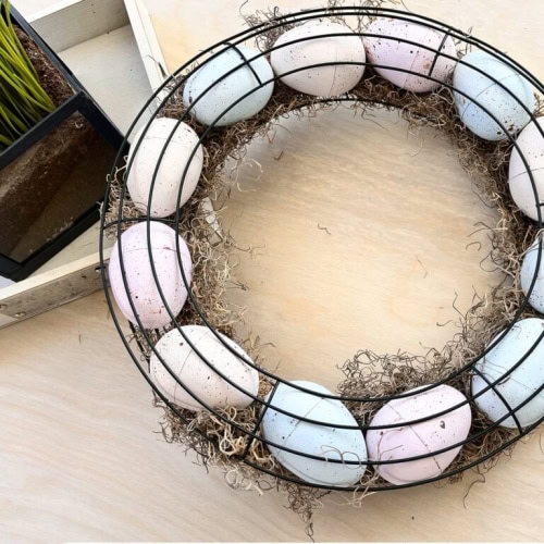 An adorable wired Easter egg wreath for Spring with DIY painted and speckled pastel colored Easter eggs in soft pink, blue and peach.