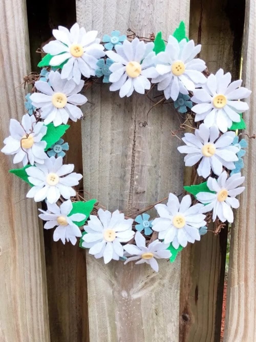 A cheerful Spring wreath craft made with white daisies, with soft green leaves.