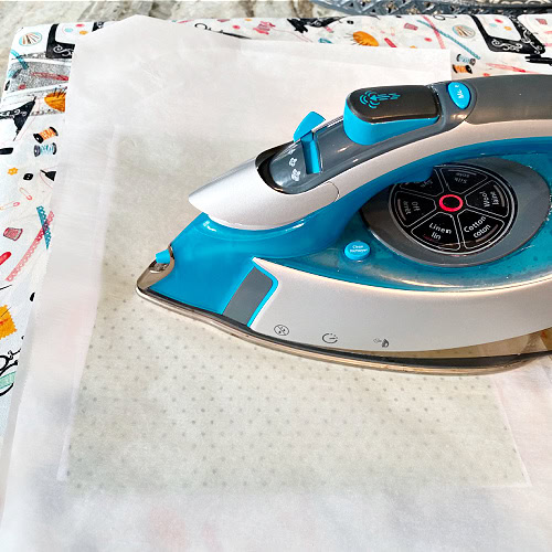 Ironing on interfacing with parchment paper protecting the iron