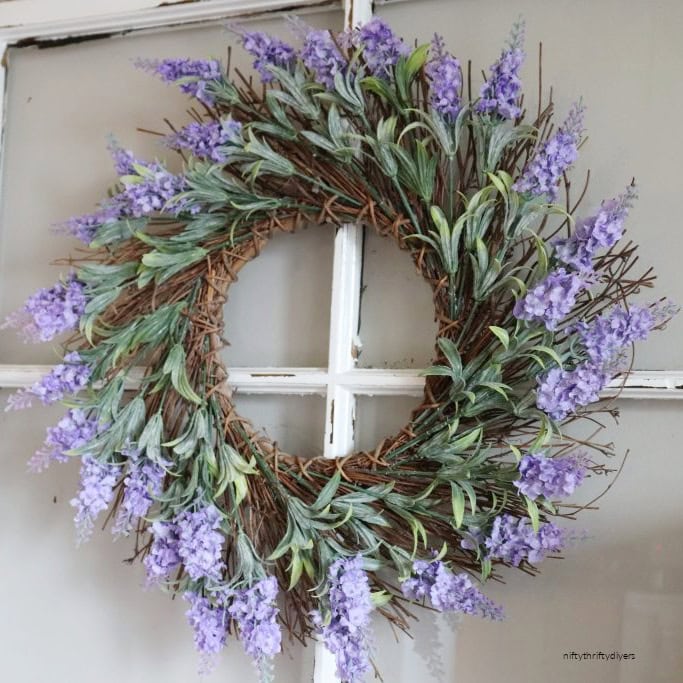 A beautiful all Lavender blossom diy Spring wreath. The background is a simple reed wreath.