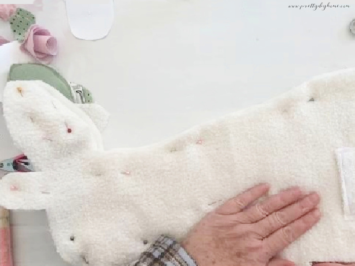 All the layer of fabric being pinned together on a bunny shaped pillow. The top layer of woven soft white fabric is showing.