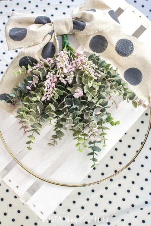 A Spring Wreath craft with a golden loops, cascading succulents, and a large black and white polka dot bow. A beautiful spring wreath for the front door.