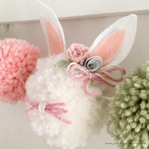 DIY rolled fabric flowers embellishing a pom pom Easter bunny craft for Spring.