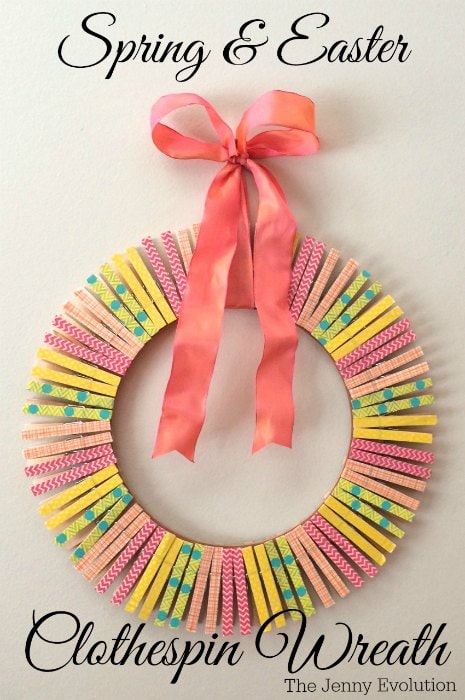 A round wreath made with assorted brightly colored, pink yellow green blue and soft pink clothespins. The closepin wreath is hunt with a pretty tangerine colored ribbon.