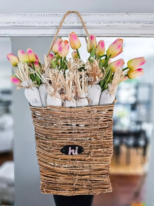 A hanging Spring basket display with a rattan basket, white carrots and tulips. A pretty DIY Spring wreath idea.