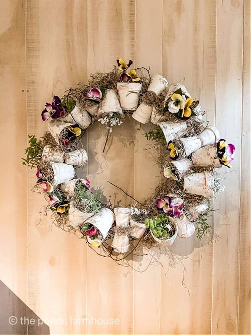 An elaborate and beautiful terra cotta pot wreath for Spring. This is a large wreath with white hand painted clay pots, faux pansies, and neutral colored moss on a twig wreath form.