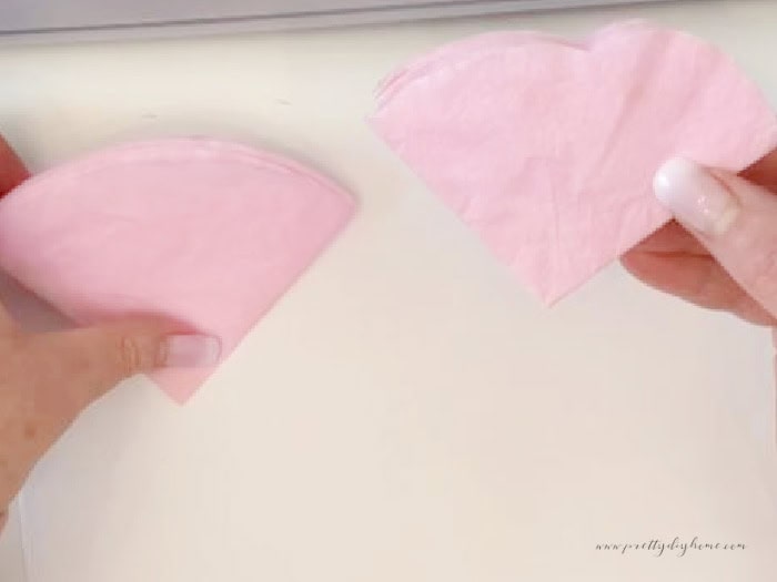 Two groups of coffee filters folded into quarters.  The one of the right is cut to look like soft petals.