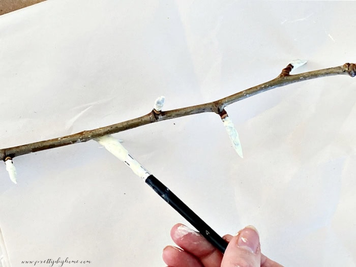 Painting the tips on a real tree branch with a soft yellow paint.