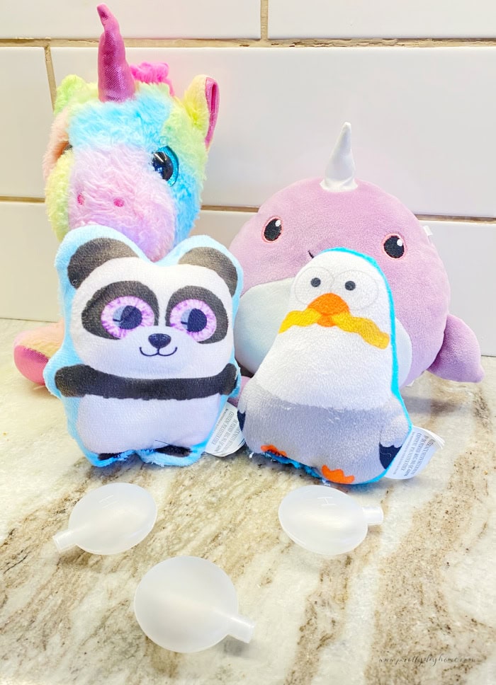 Four different thrift store stuffed toys sitting on a counter with DIY dog toy squeakers in front of them.