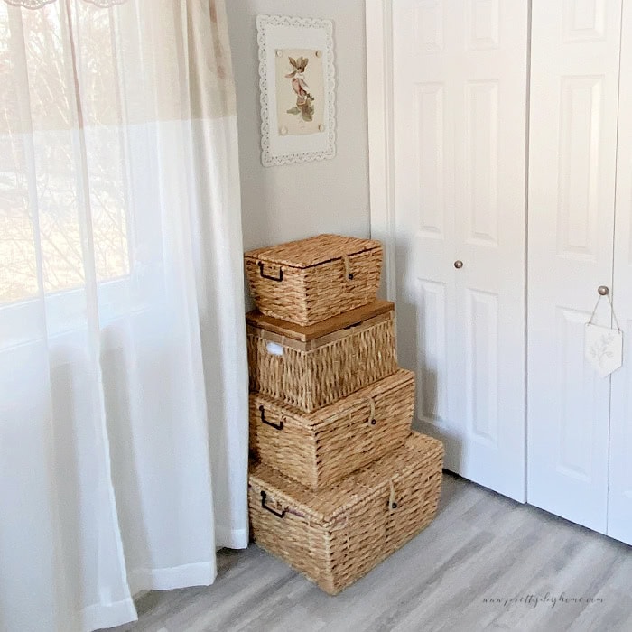 A set of four golden brown rattan stacking baskets with lids.  They are being used to store fabric.