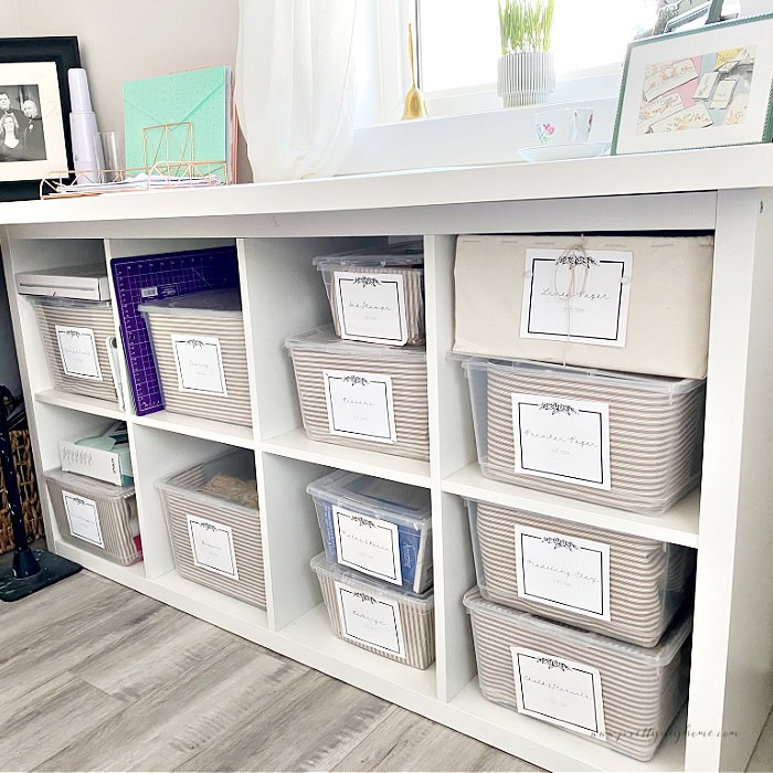 An IKEA Kallax shelf on its side with a table top as part of a DIY craft room desk.  Its filled with 20 plus storage bins for craft room storage.