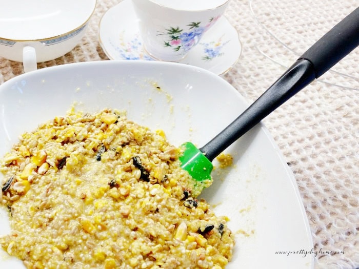 Mixing bird food and suet together while making a teacup bird feeder.
