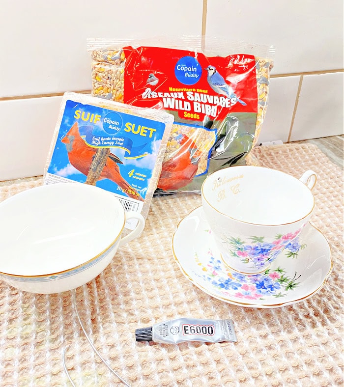 Supplies for making suet tea cup bird feeders including E 6000 vintage teacups, wild bird seed and a package of suet.