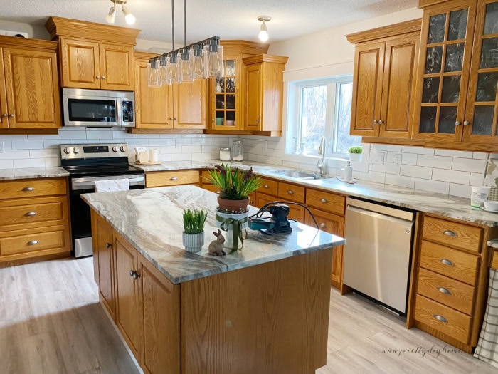 A large kitchen with oak cabinets that is still quite dark inspite of new floors and granite.