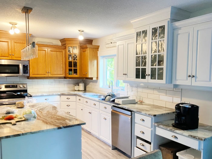 Painted kitchen cabinets where one section is done and the next section is not painted. Illustrating how to paint a kitchen in smaller sections.