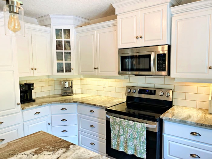 A kitchen with white diy painted cabinets and stainless steel appliances.