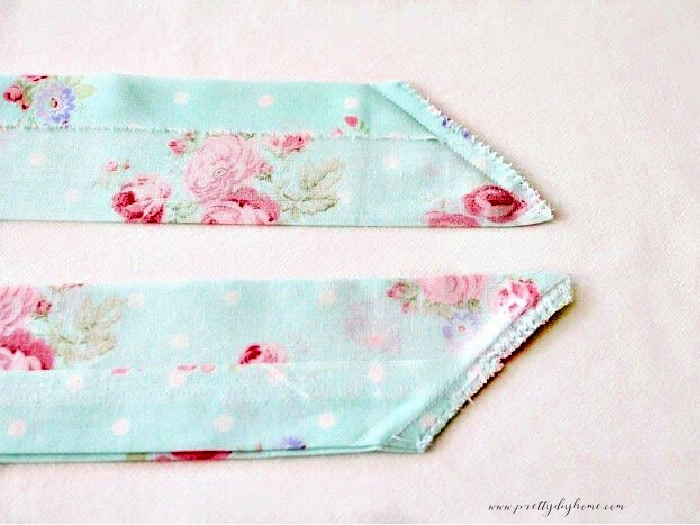 The ends of two apron ties each cut at an angle and sewn with a zig zag stitch at the end.