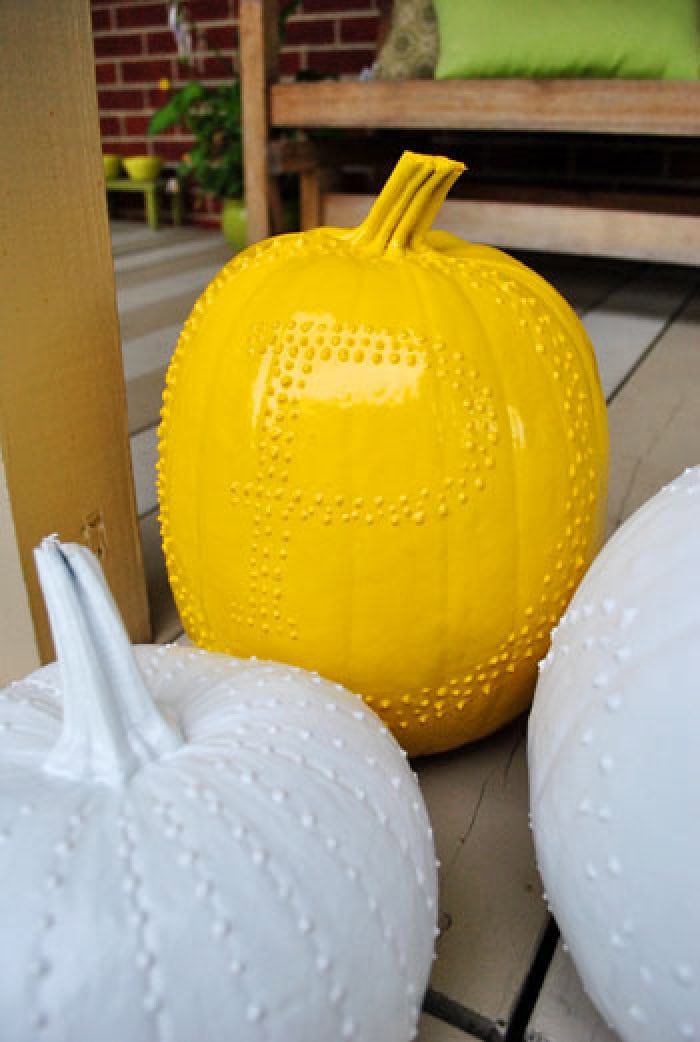 Three painted pumpkins with long stems, two are white and one is golden orange they are all decorated for fall with puff paint. Each pumpkin has a fun pattern placed on it using dots of puff paint in different symetrical patterns.