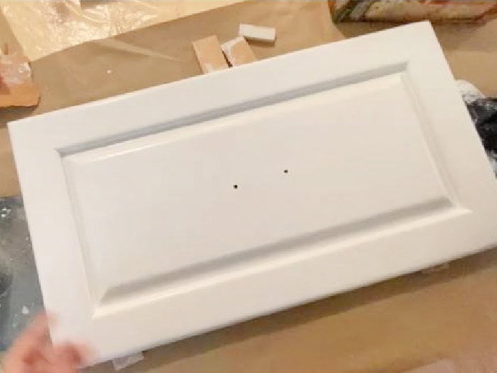 A kitchen cabinet door thats been elevated to reduce runs while painting.