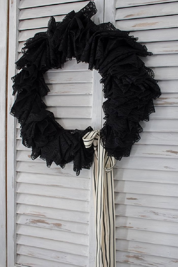 An elegant Halloween wreath made with black lace and black and white striped ribbon bow.