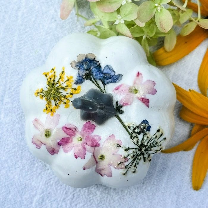 A top view of a beautiful white pumpkin decorated with multicolored dried flowers.