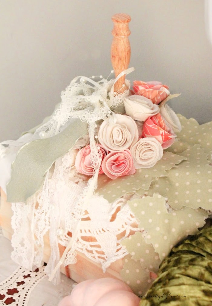A handmade pumpkin for fall with flowers cascading down the side. The pumpkin is in soft whites, cream, pinks and green.