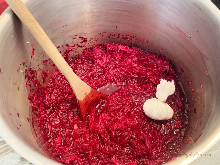 A large pot filled with the ingredients for beet and horseradish relish.  You can see a cheesecloth bundle of pickling spice added.