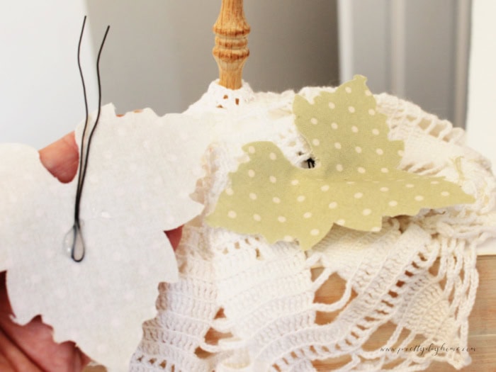 Adding fabric leaves to a pumpkin diy craft. you can see the pumpkin leaf with wire attached and the placement of the first pumpkin leaf.