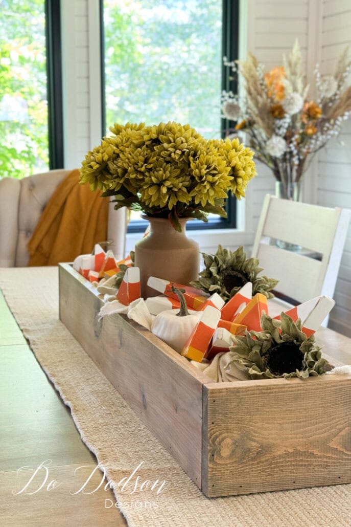 A wood box sitting on a table filled with handmade wood candy corn decorations,