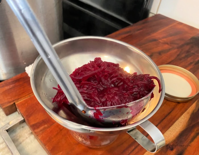 Adding a ladel full of homemade beet and horseradish relish to a funnel for canning.