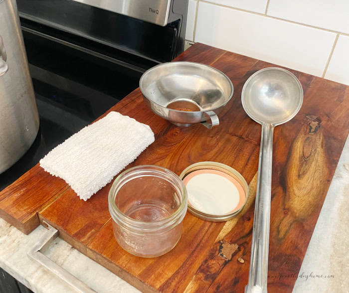 Supplies needed for canninng  beet and horseradish relish.  A large board to work on covered with a jar, lid, ring, ladel, funnel and clean cloth.