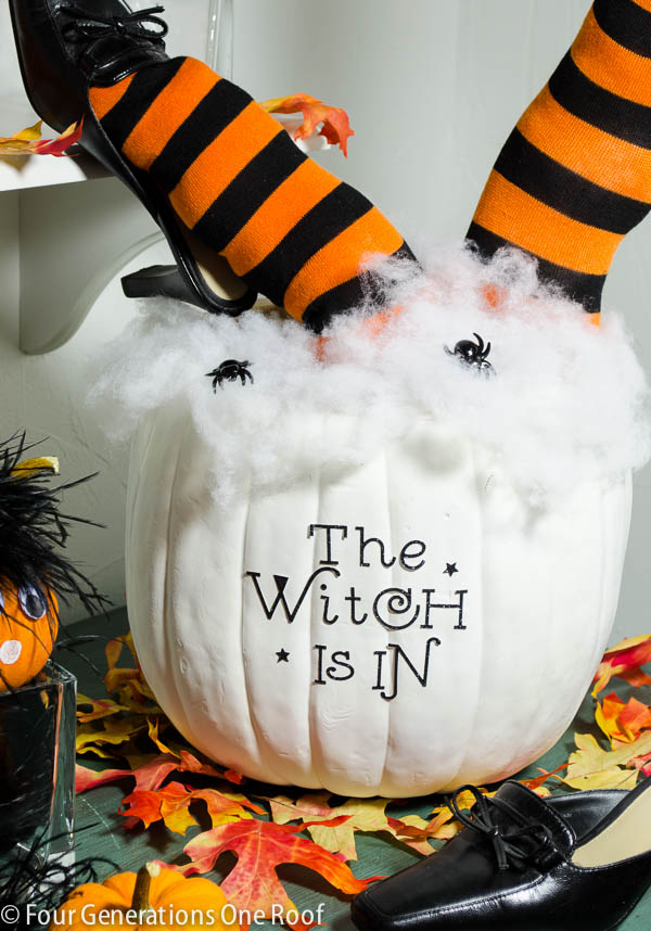 A very cute pumpkin witch centerpiece made with a large white pumpkin, that says the witch is in  There are two cute witches legs sticking out the top with orange and black stiiped socks and black shoes.