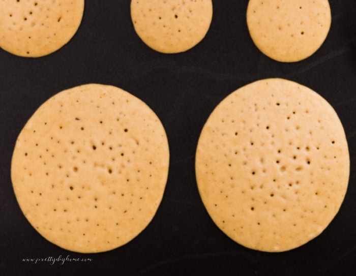 A pancake griddle covered with large and small pumpkin pancakes. You can see they are ready to turn over because of little dots in the batter.