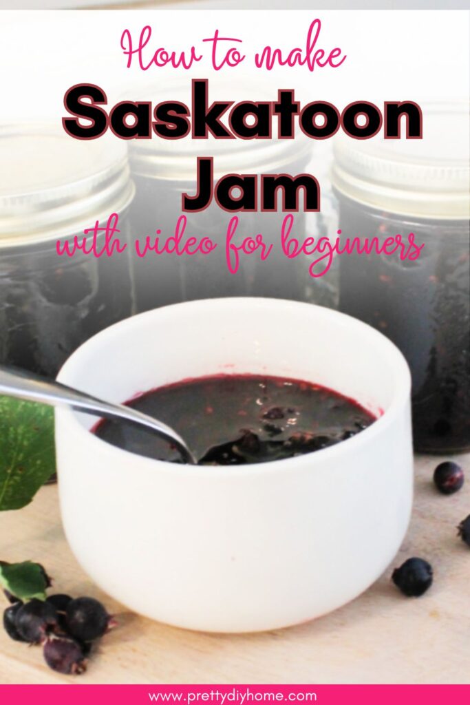 A small bowl filled with thick and juicy homemade saskatoon berry jam. There are three jars of homemade jam in the background.