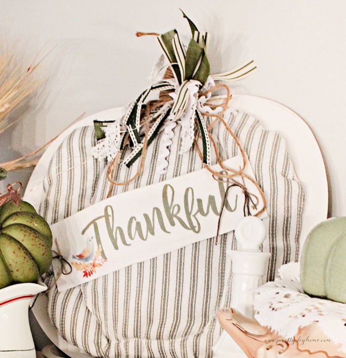 A beautiful Fall pumpkin diy, made using fabric and a wood dollar tree pumpkin. Its in neutral fall colors, like white cream and green and features a matching green messy bow.