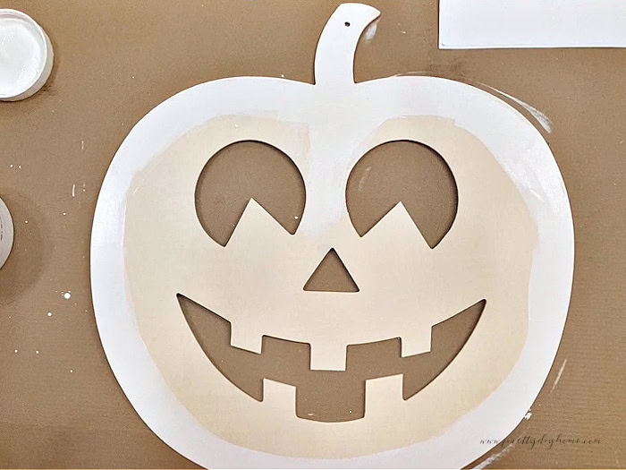 A wood pumpkin cut out with the outer edges painted white.