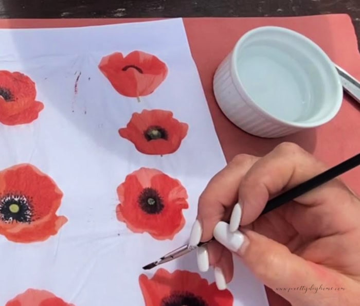 Using water and a small paint brush to weaken the outside edges of a poppy printable. This will make it easier to rip.