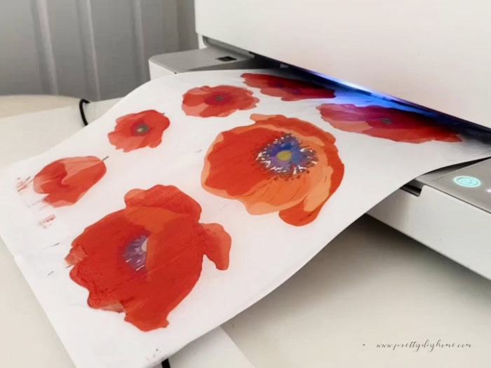 Poppy printables in bright orange and red being printed. The transfer is coming out of the front of the printer showing the seven poppy printables.