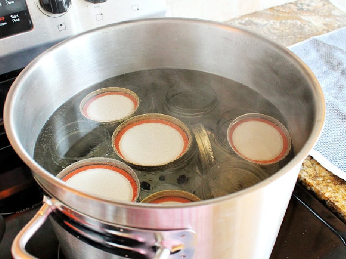 A large pot full of boiling water, pint sized canning jars, lids and rings being sterilized for canning beet and horseradish relish.