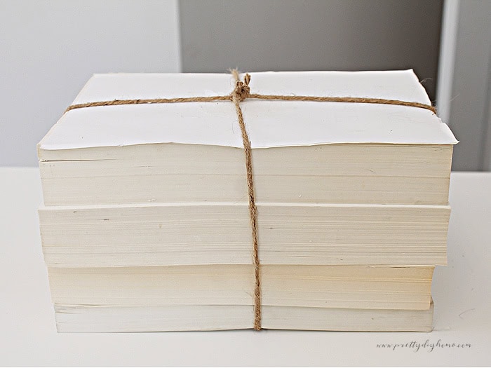 A stack of thrifted books with the covers torn off. Their are four books ties together with twine.
