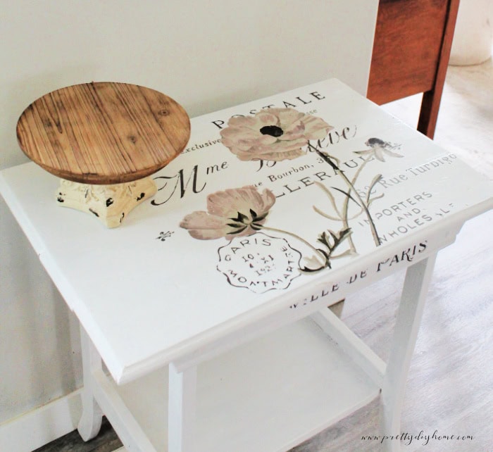 A closeup of vintage french graphics on a antique side table makeover, that was in terrible condition. The table is painted white.